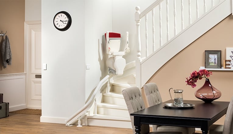 Un monte-escalier sur un escalier dans le salon. Un monte-escalier s'adapte à presque tous les escaliers, tandis qu'un ascenceur à domicile ne convient pas à toutes les maisons.