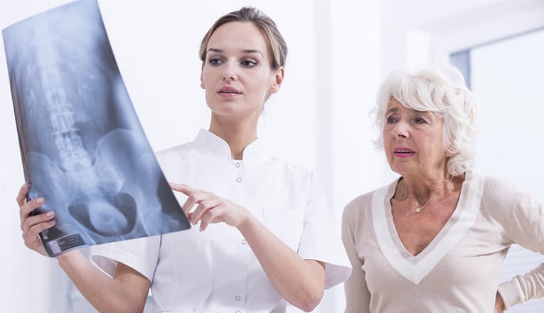 un médecin montre une IRM à une femme qui se plaint d'arthrose du dos.
