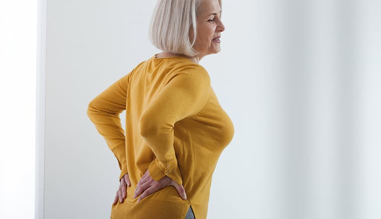 Madame présente des symptômes d'arthrose du dos tels que des courbatures et des douleurs.