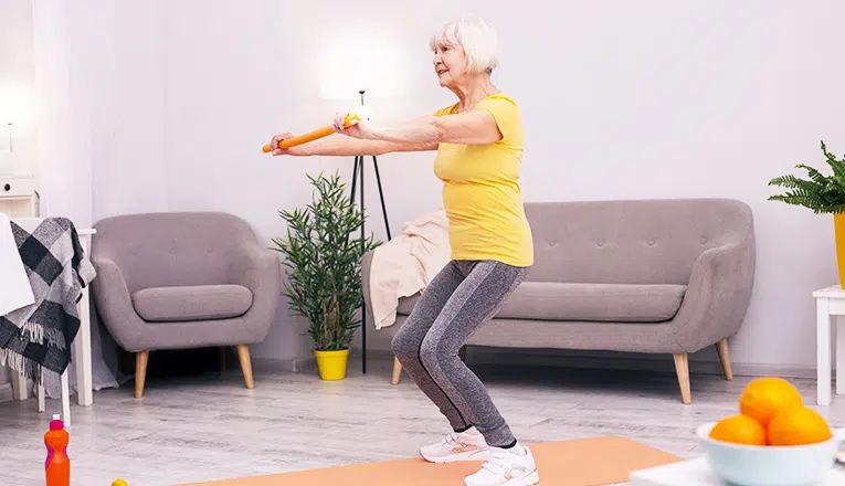 Une femme âgée fait des squats comme exercice de remise en forme