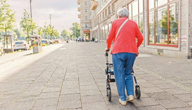 femme agee avec un déambulateur solitaire dans la rue